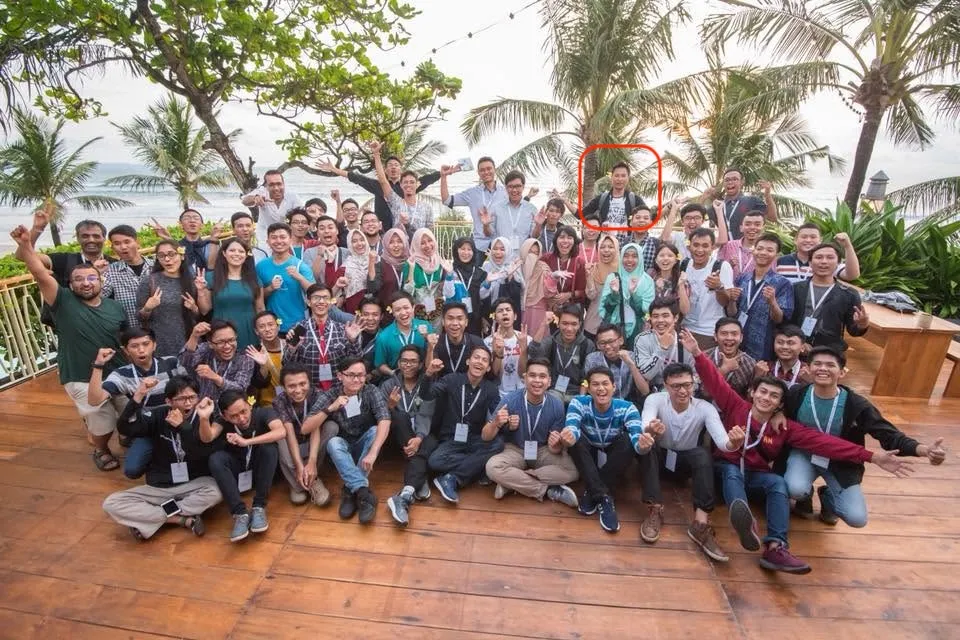 A large group of Developer Student Club leads posing on a wooden terrace by the beach